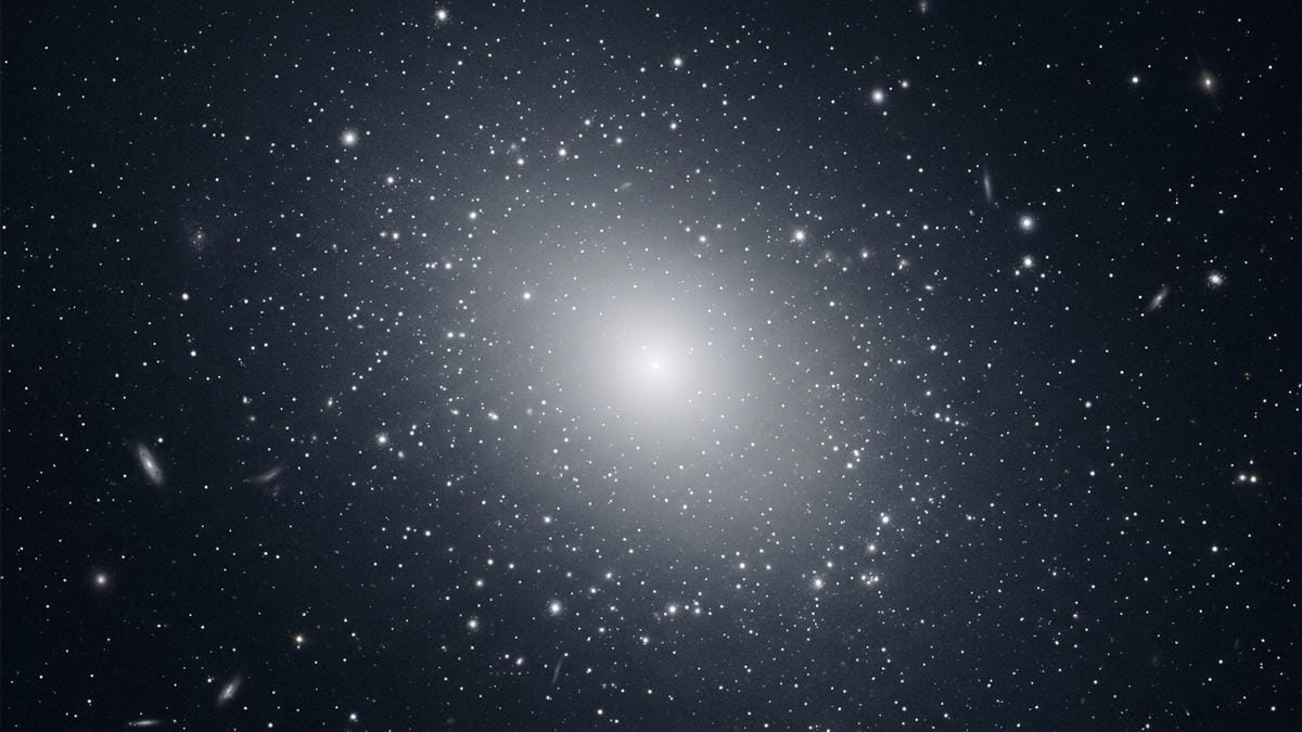 Vista amplia de una galaxia elíptica con numerosos cúmulos globulares alrededor, en un entorno científico sobrio y legible.