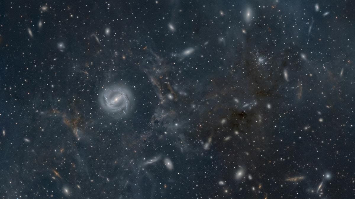 Representación de una galaxia joven, rica en gas, con una barra estelar insinuada en su interior bajo un campo profundo del universo temprano.