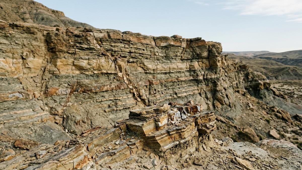 Paisaje geológico antiguo con estratos sedimentarios y una capa mineral alterada, sugiriendo el contexto donde una firma isotópica de nitrógeno podría preservarse o deformarse.