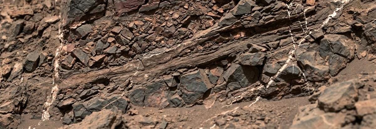 Detalle de capas rocosas fracturadas y fragmentos superpuestos que sugieren impactos antiguos en Marte