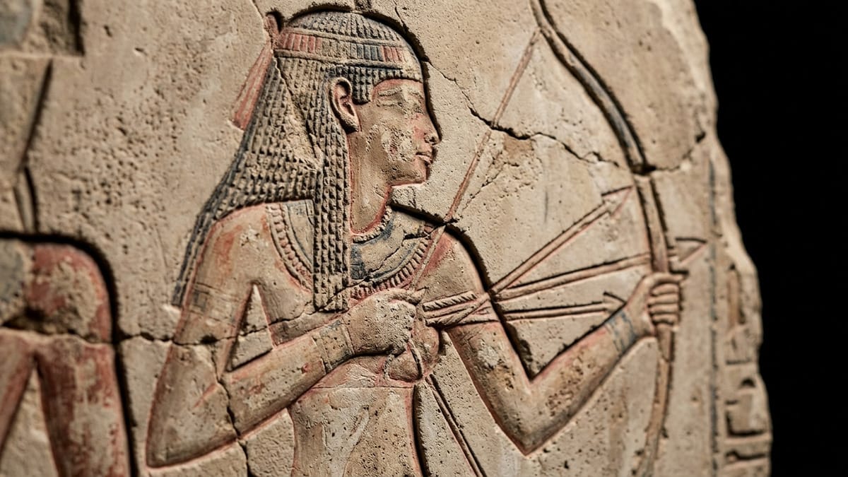 Detalle cercano de una figura real egipcia con arco en una escena de relieve, vista como evidencia simbólica.
