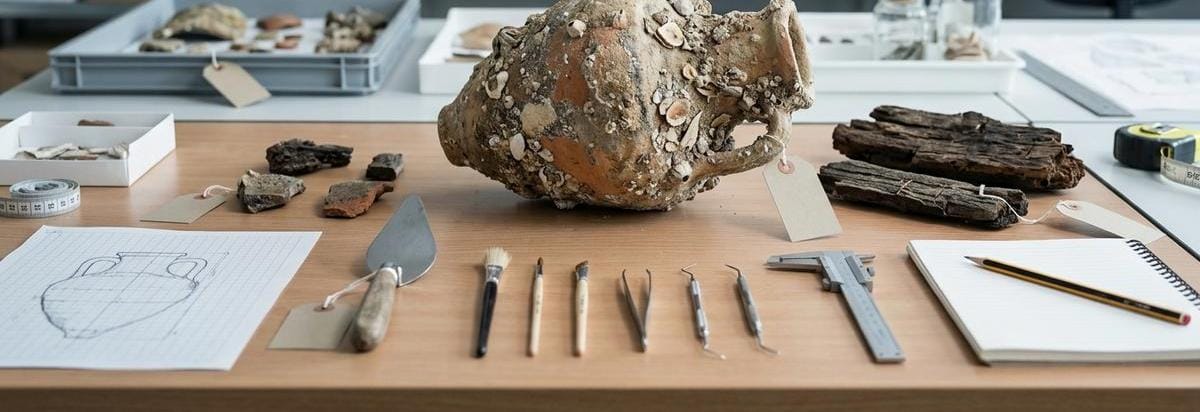 Fragmentos arqueológicos medievales de Menorca analizados sobre una mesa de laboratorio con herramientas de catalogación.