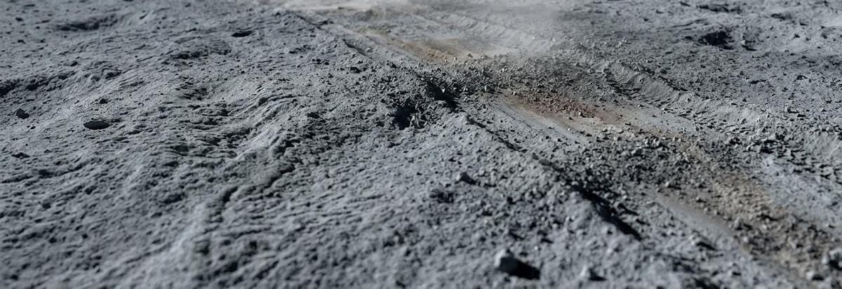 Una estela de polvo lunar levantada por ruedas de un rover sobre un terreno cercano a una zona de muestreo, sugiriendo la tensión entre exploración y preservación.