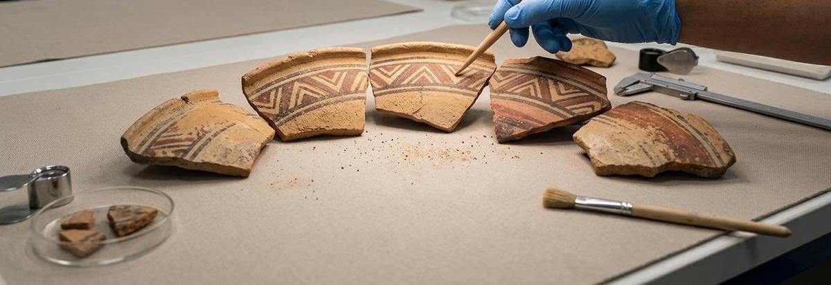 Detalle de cerámicas fragmentadas con líneas de comparación y luz de laboratorio arqueológico