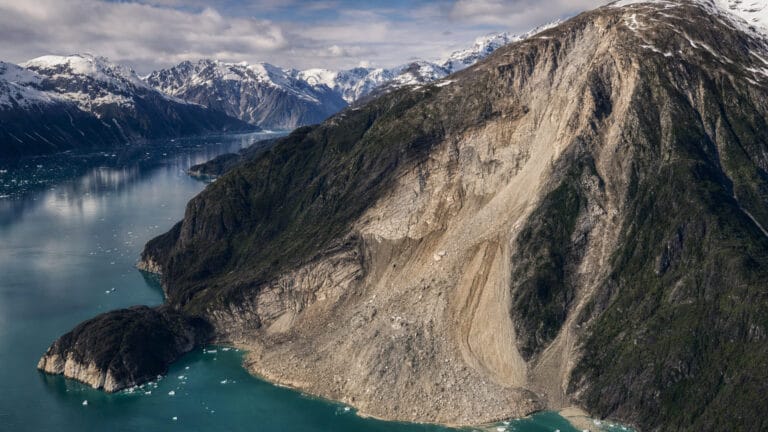 Ilustración de un fiordo de Alaska con la ladera opuesta marcada por el run-up de un tsunami tras un deslizamiento.
